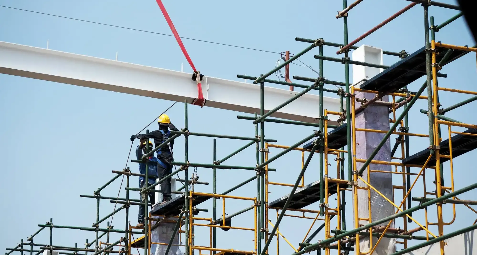Workers on an erected scaffold platform with guardrails against open sky